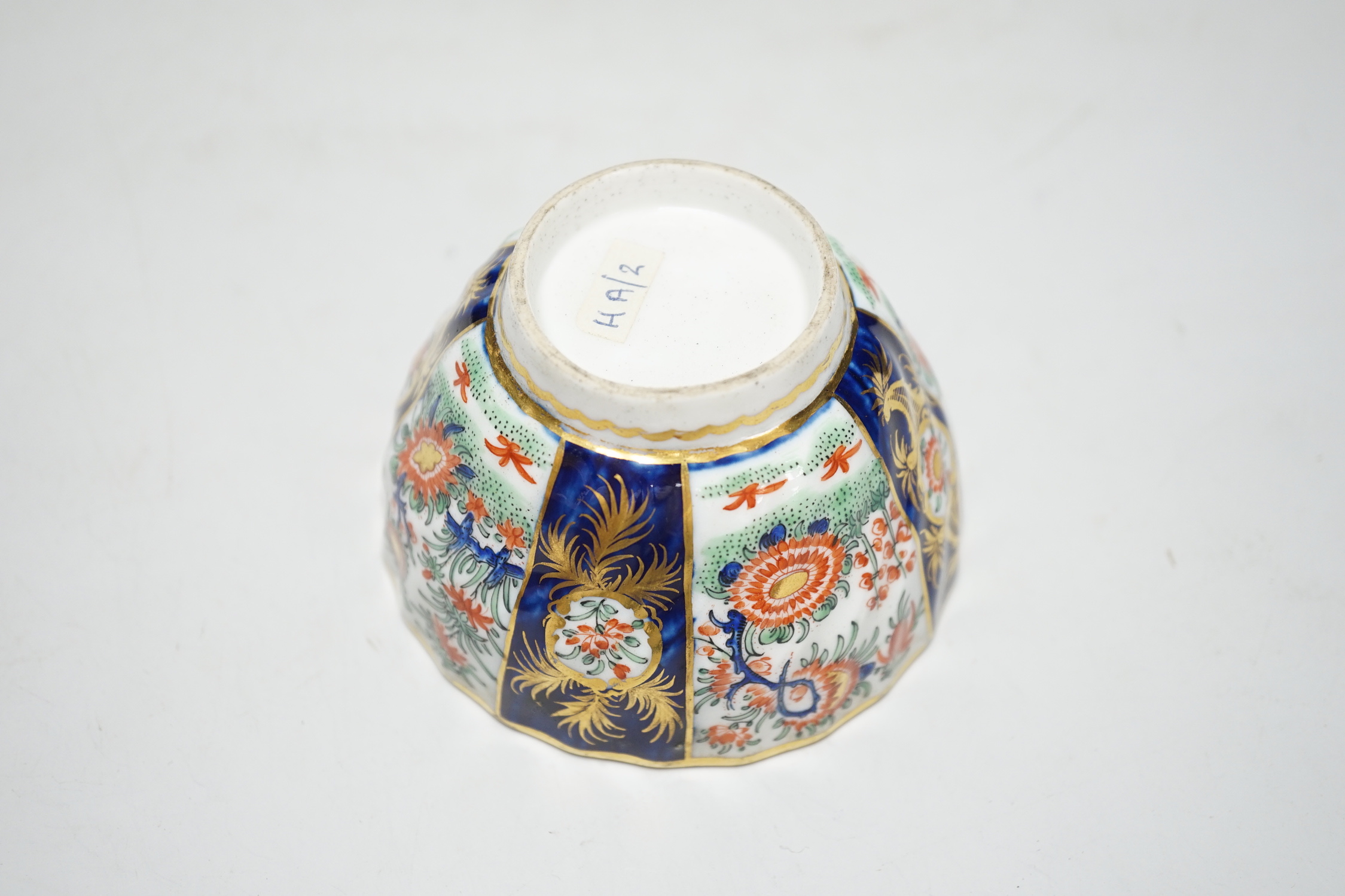 A Chamberlains Worcester good kakiemon style teabowl and saucer painted with oriental flowering plants in fan shaped panel, c.1785-90